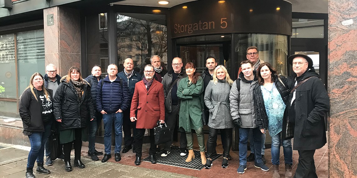 En grupp på 16 personer i ytterkläder utanför porten på Storgatan 5 i Stockholm.