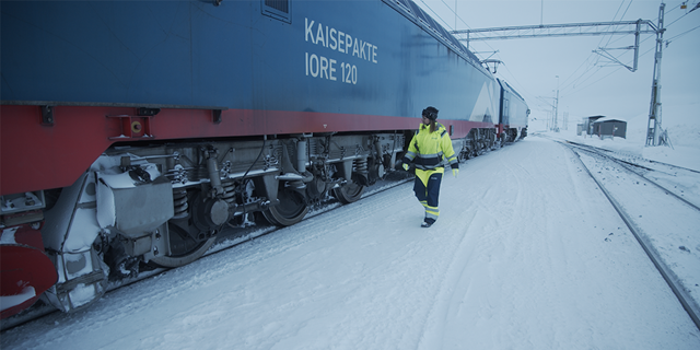 Industriarbetare promenerar i snö vid godståg