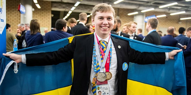 Martin Lindelöw, 20-årig industrielektriker, står insvept i en svensk flagga med sina två medaljer om halsen.