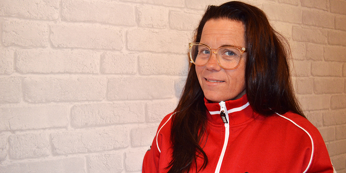 Porträtt av Anna Björklund i röd jacka framför vit tegelvägg.