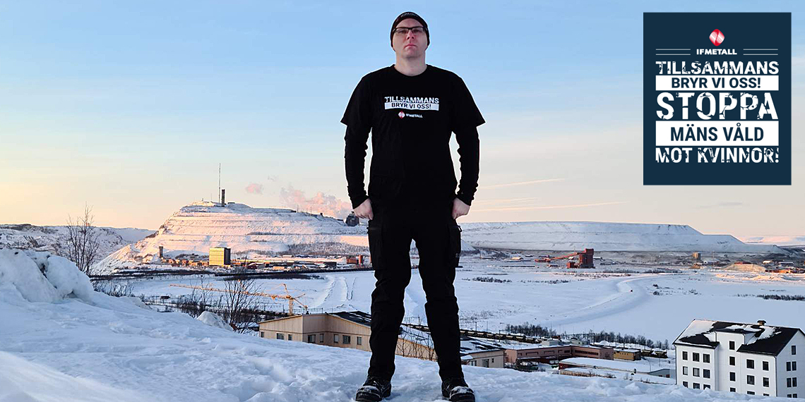 Person i klädd IF Metalls kampanjtröja, stående  på en höjd med Kirunas gruva i bakgrunden.