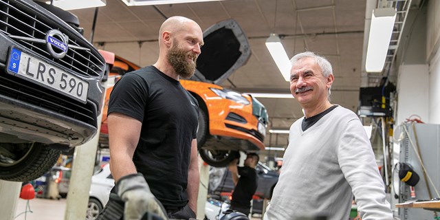 Två män på en arbetsplats där bilar repareras.