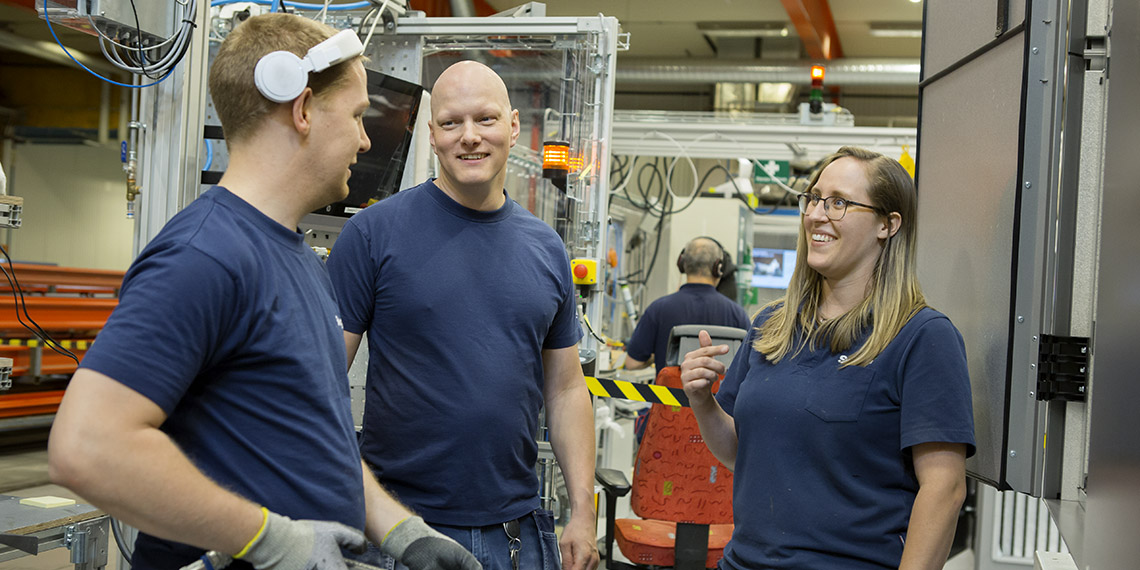 Rasmus Svensson och Veronika Härling pratar med en kollega på Swegon i Kvänum.