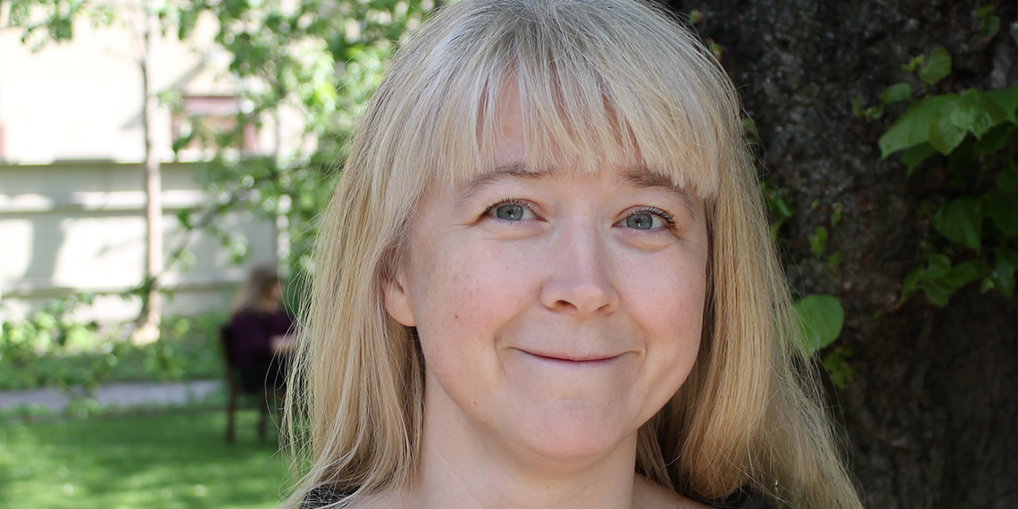 Utomhusfotografi av kvinna framför trädstam.