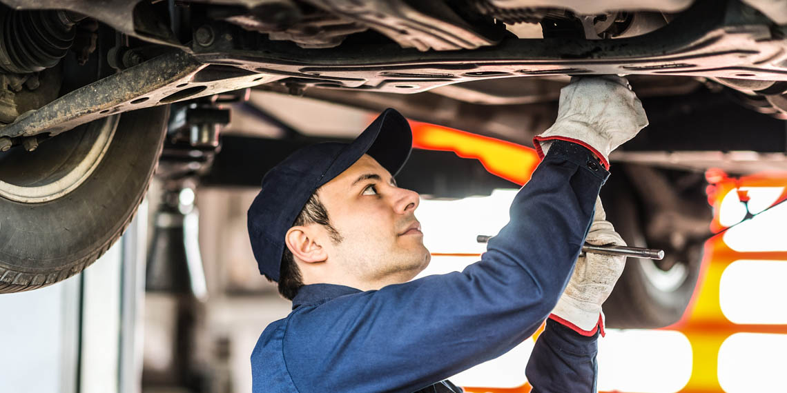 Bild på en man som meckar under en bil