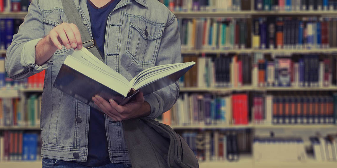 En som läser framför en bokhylla