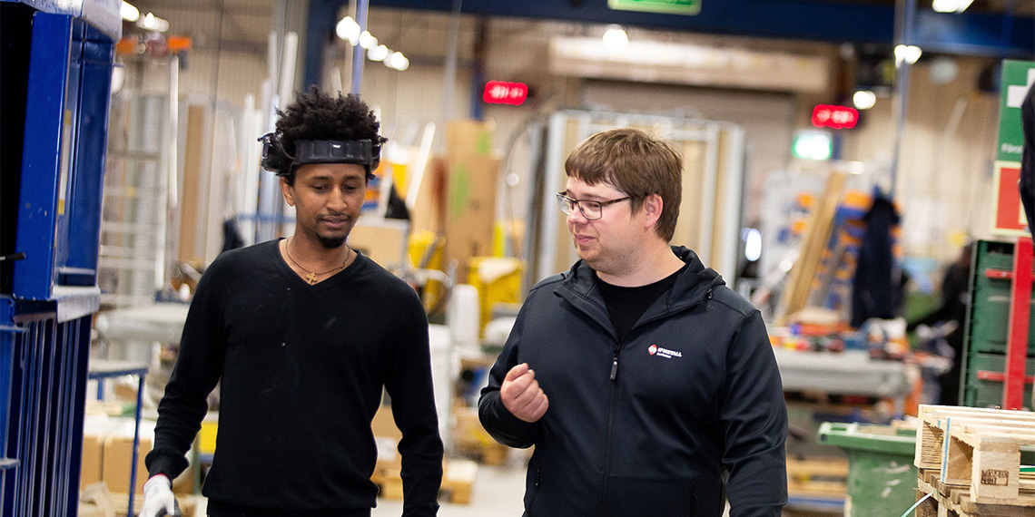 Två personer samtalar på arbetsplats.