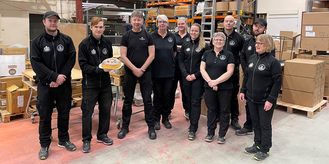 Flera personer från Skultuna. En av personerna håller i en tårta