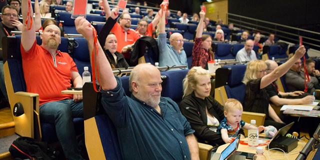 Bild från kongressen 2017. Flera personer sitter i en aula och röstar genom att hålla upp en lapp.