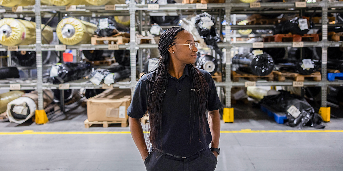 Bessie Gondwe står på ett lager och tittar åt sidan.