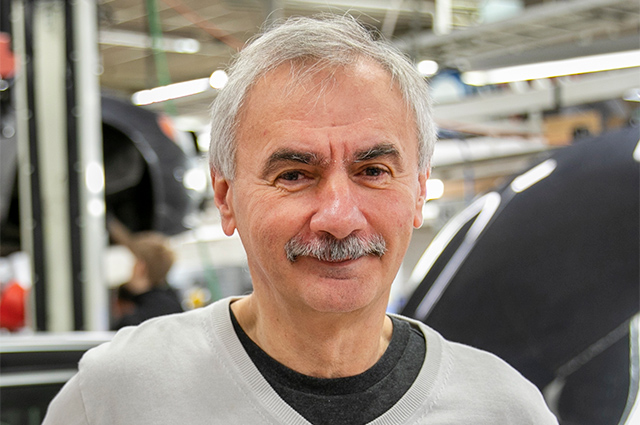 Gråklädd person på arbetsplats i fordonsindustrin.