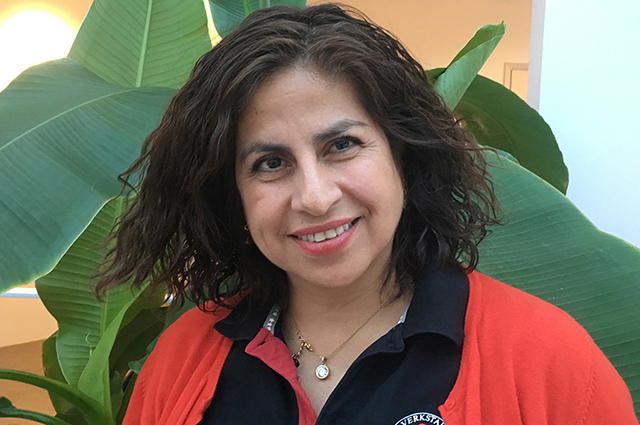 Person med röd jacka framför stora gröna växter.